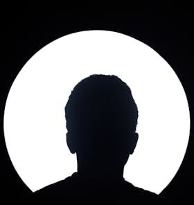 Artistic silhouette of an unknown person against a bright circular light background.